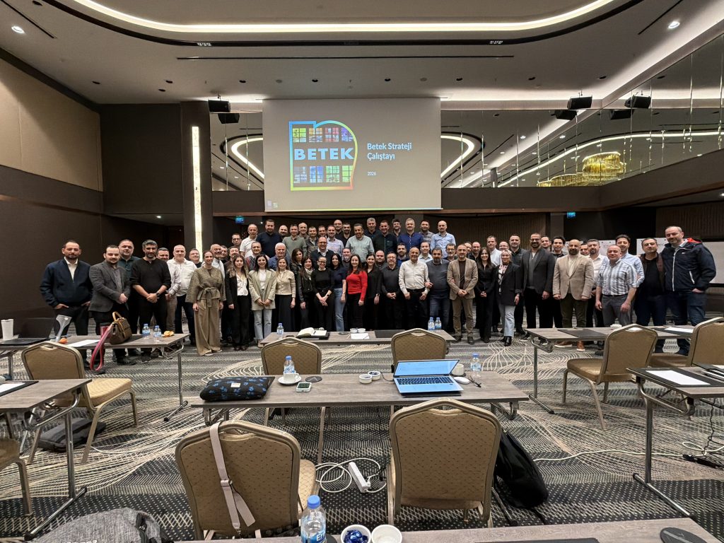 A large group of Betek employees posing for a photo inside a conference room.