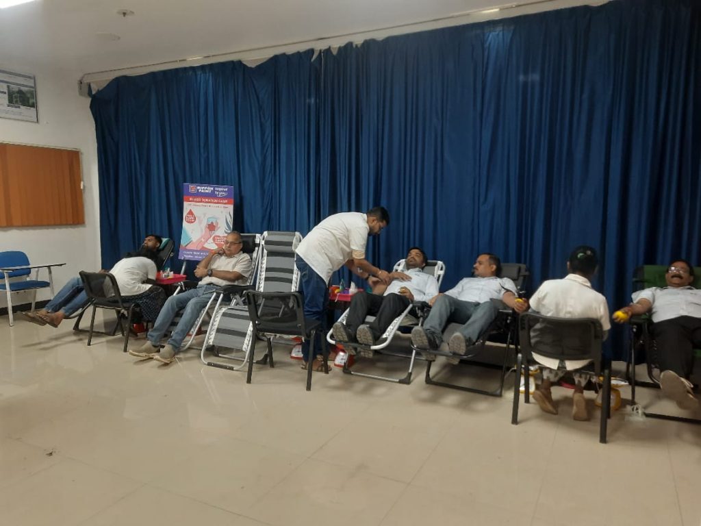 Several employees lying back on medical chairs donating blood while medical staff assist them.