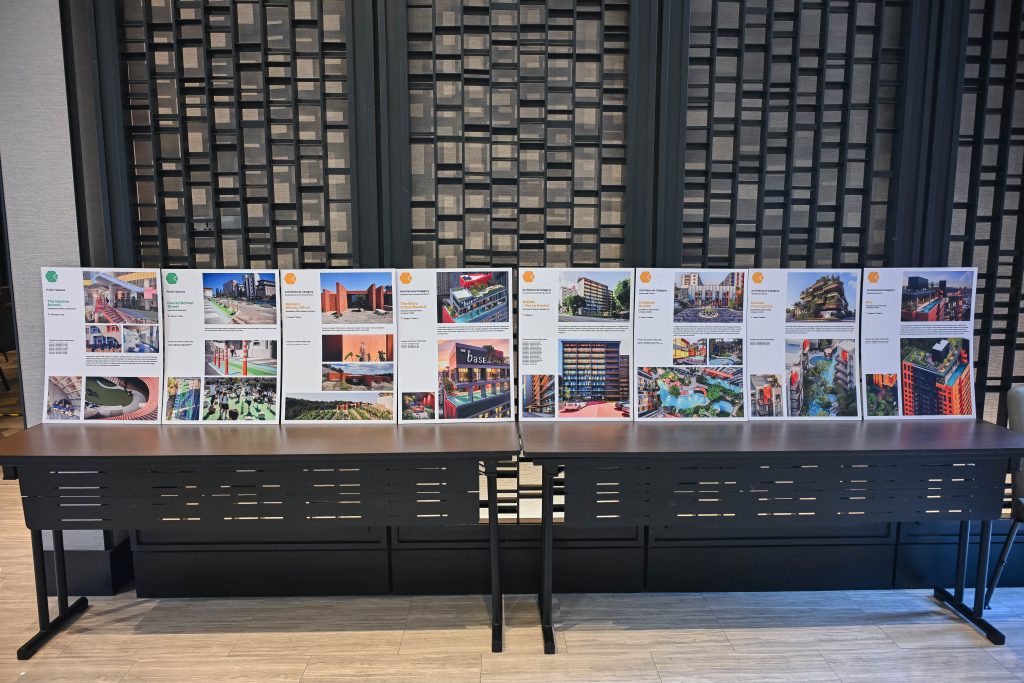 A row of printed architectural presentation boards lined up on black tables in a well-lit room.