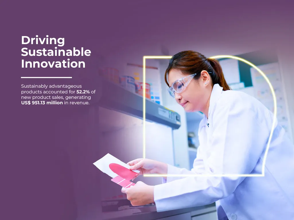 A female laboratory technician in safety goggles and a white coat reviewing colour swatches.